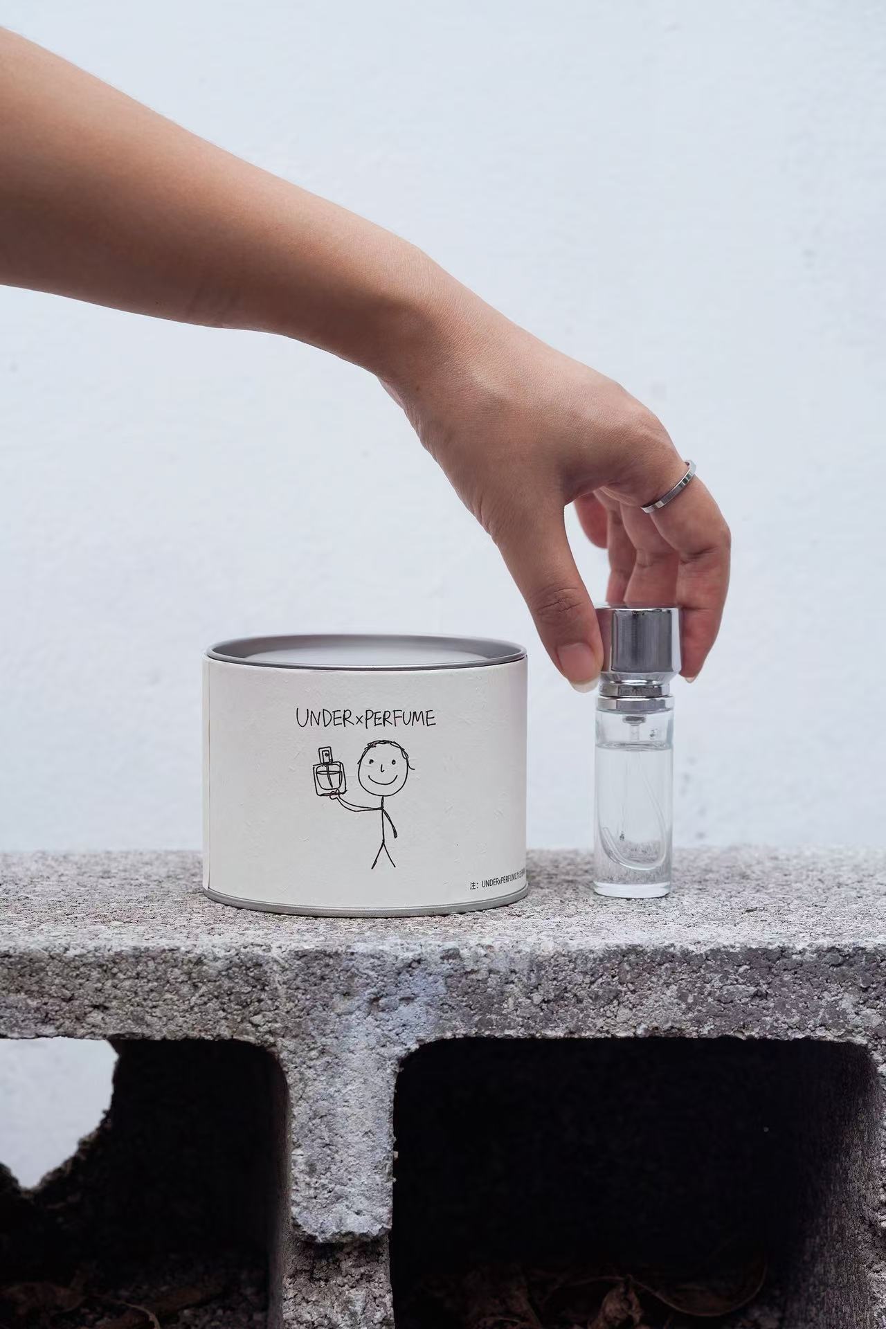 Hand holding a small perfume bottle beside packaging